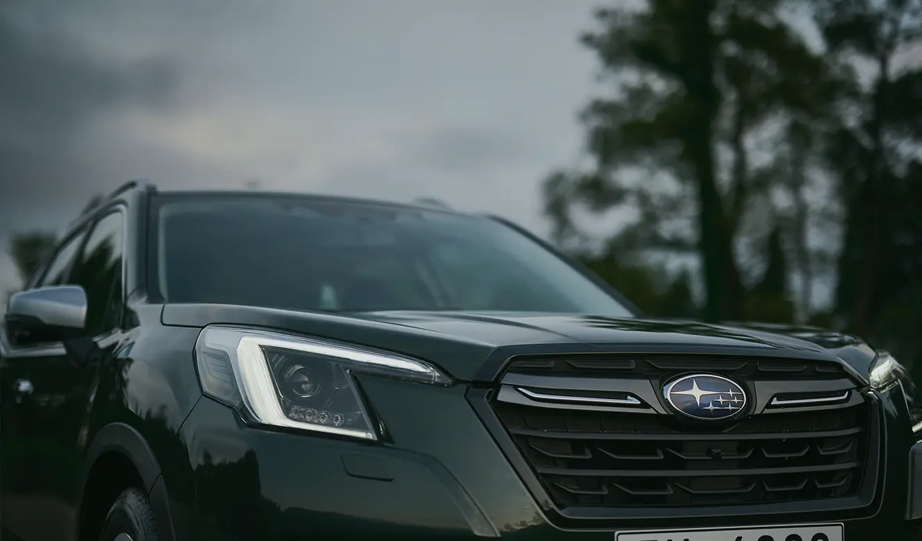 Parte delantera de Subaru Forester camioneta híbrida con árboles de fondo.