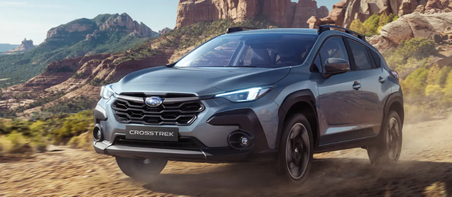 Modelo Subaru Crosstrek Hybrid en carretera todo terreno con montañas de fondo. 