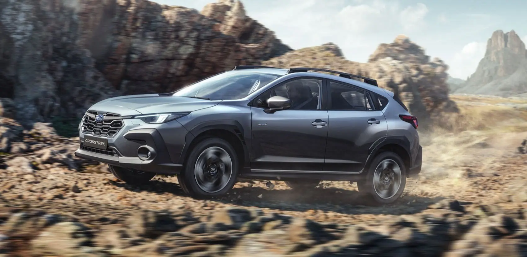 Subaru Crosstrek en terreno arenoso con piedras de fondo. 